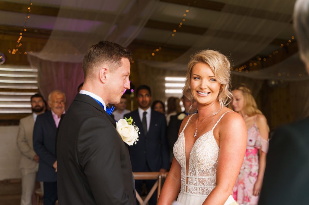 Bride smiling during the wedding ceremony at Furtho Manor Farm